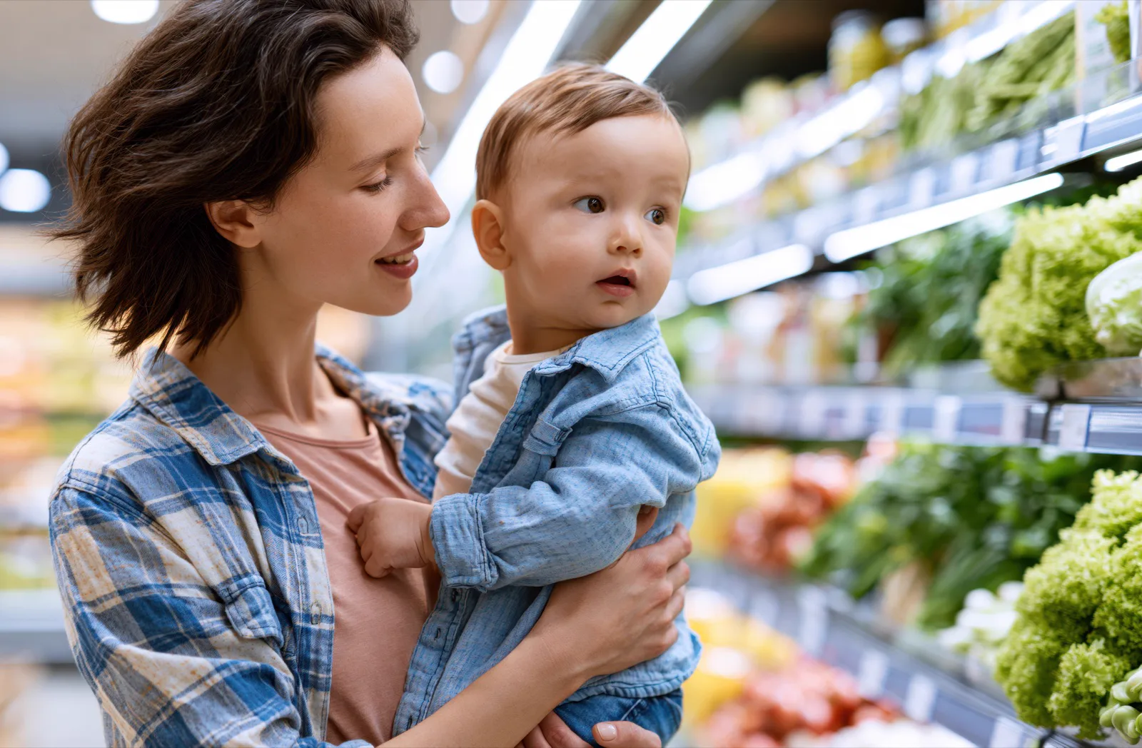 Alltag mit Baby Mutter trägt ihr Baby beim Einkaufen im Supermarkt